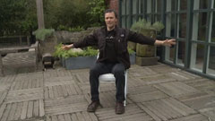 Danny O'Brien demonstrating a technique on a chair, arms outstretched